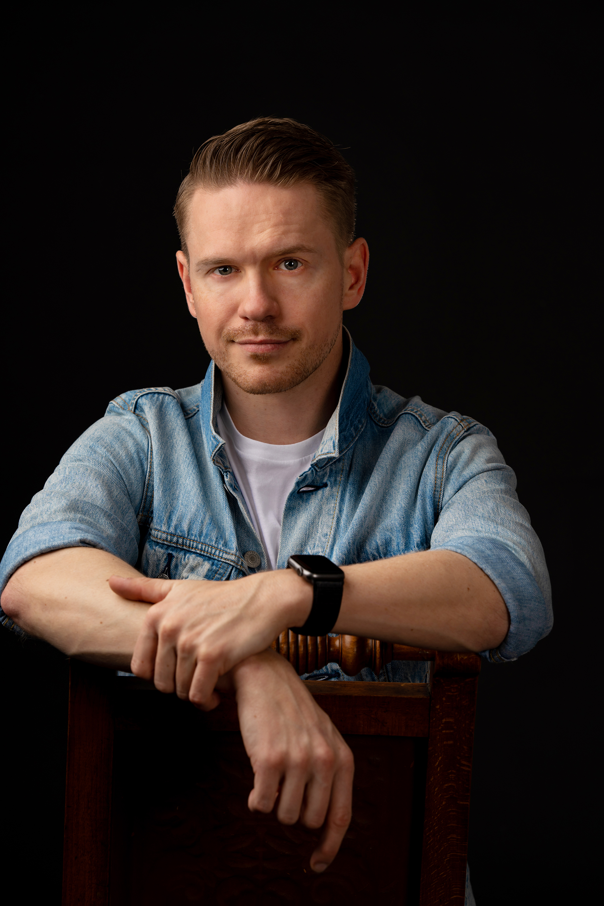 Andreas leaning on a chair.